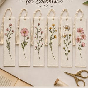 May include: Six rectangular fabric bookmarks featuring hand embroidery designs of various flowers including daisies and cosmos. Each bookmark has a cream-colored base, green stems, and a matching tassel at the top. Text reads 6 Designs Hand Embroidery Design for Bookmark.