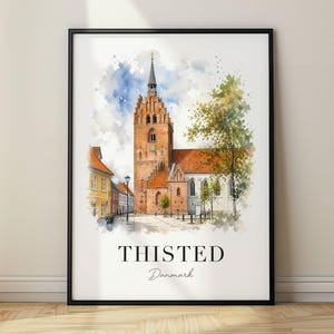 Op de afbeelding: Een ingelijste aquarel kunstdruk met een historische bakstenen kerk met een hoge toren in Thisted, Denemarken. De afbeelding toont een geplaveide straat, een geel gebouw en groene bomen, met de tekst THISTED Danmark onder de afbeelding gedrukt.