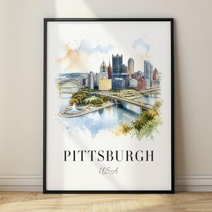 May include: A framed wall art print featuring a watercolour illustration of the Pittsburgh skyline, including the Point State Park fountain and bridges. The text PITTSBURGH USA is printed in black at the bottom of the white background.
