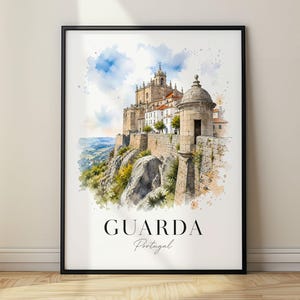 May include: A framed watercolor art print depicting the historic stone cathedral and fortress walls of Guarda, Portugal, perched on a rocky cliffside under a blue sky. The text "GUARDA Portugal" is printed in black at the bottom of the image.