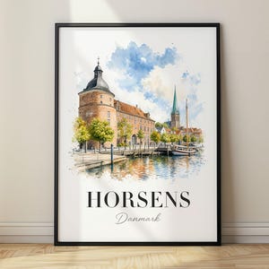 Op de afbeelding: Een ingelijste aquarelprint met een stadsgezicht van Horsens, Denemarken, met een historische bakstenen toren, een haven met een boot en groene bomen. De tekst 'HORSENS' staat in grote zwarte letters, gevolgd door 'Danmark' in cursief.