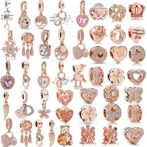 Può includere: Una collezione di ciondoli e pendenti in oro rosa, con vari design come cuori, corone, fiori e forme astratte. Alcuni ciondoli sono impreziositi da cristalli trasparenti.