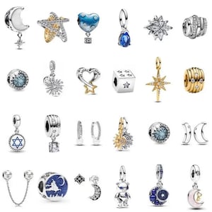 Può includere: Una collezione di ciondoli e orecchini argentati e dorati. I design includono lune, stelle, cuori e un orso. Alcuni ciondoli presentano pietre preziose blu e trasparenti. I gioielli sono progettati per bracciali e collane.
