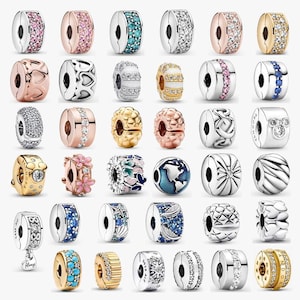 May include: A collection of thirty-six metal charm beads in various designs, including pavé-set stones, floral motifs, heart patterns, and geometric shapes. The charms are rendered in silver, gold, and rose gold tones with colorful accents.