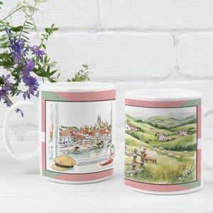 May include: Two white ceramic mugs with scenic illustrations. One mug shows a European cityscape with a river, buildings, and a hat. The other mug depicts a pastoral scene with sheep, a fence, and rolling green hills.
