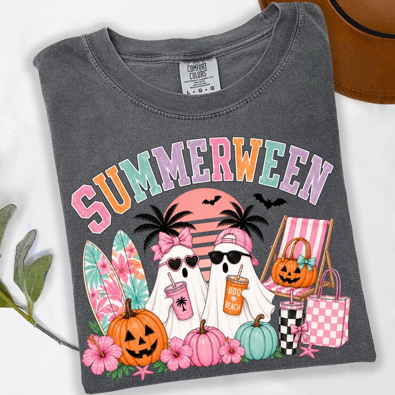 May include: A charcoal gray t-shirt featuring the text SUMMERWEEN in pastel letters. The graphic includes two ghosts, one wearing a pink bow and heart sunglasses, the other a pink cap and black sunglasses, holding drinks, with pumpkins, surfboards, and beach gear.