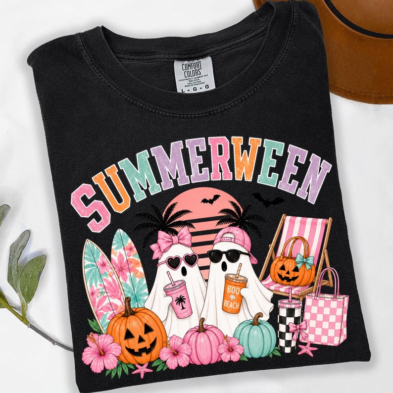 May include: A black t-shirt featuring the text SUMMERWEEN in colorful letters. The graphic includes two ghosts wearing sunglasses and hats, surfboards, jack-o'-lanterns, a beach chair, a checkered cup, and a pink checkered tote bag.
