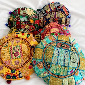 Puede incluir: Una colección de cinco cojines de suelo redondos con intrincados diseños de patchwork, bordados vibrantes, lentejuelas y pequeñas borlas. Los cojines muestran varias paletas de colores que incluyen amarillo, turquesa, verde, rojo y azul, con detallados patrones florales y geométricos cosidos en las superficies de tela.