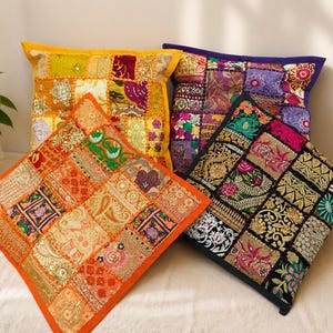 Peut inclure: Quatre coussins carrés présentant des motifs en patchwork avec des broderies complexes, des paillettes et des accents de fils métalliques. Les coussins sont disposés en groupe, affichant des palettes de couleurs vives dont jaune, orange, violet et noir.