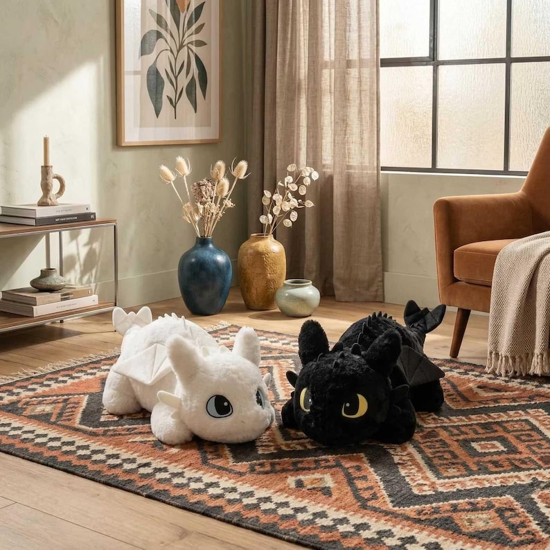 May include: Two plush dragon toys, one white and one black, are displayed on a patterned rug. The white dragon has blue eyes and white wings. The black dragon has yellow eyes and black wings. The toys are in a living room setting.