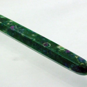 May include: A green, faceted, crystal point with white and purple inclusions. The crystal is about 4 inches long.