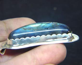 Puede incluir: Un colgante de plata con una piedra preciosa de labradorita azul y verde engastada en un engaste de plata festoneado.