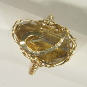 May include: A gold ring with a large, clear, faceted gemstone set in a twisted wire design.