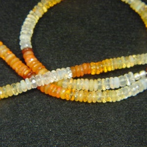 May include: A multi-strand necklace made of small, round, white, yellow, and orange opal beads.