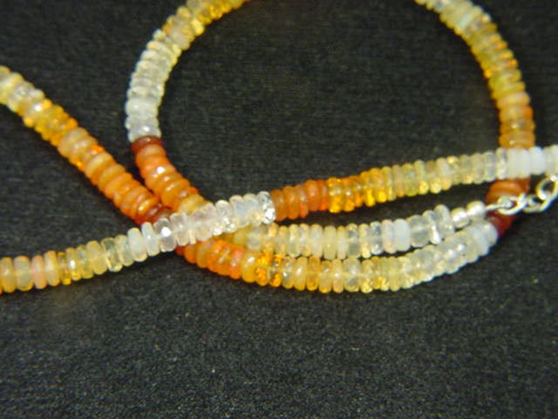 May include: A multi-strand necklace made of small, round, white, yellow, and orange opal beads.