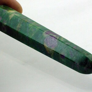 May include: A green and purple gemstone wand with a pointed tip. The wand is approximately 5 inches long and has a faceted shape.