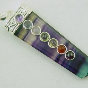 Puede incluir: Un colgante de plata con una piedra de fluorita púrpura y verde y siete piedras de chakra. Las piedras son amatista, cuarzo transparente, cuarzo rosa, aventurina verde, citrino amarillo, cornalina y jaspe rojo.