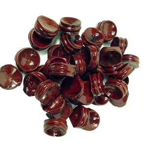May include: A collection of small, round, dark red wooden display stands. Each stand has a circular top and a base with a carved design. The stands are arranged in a pile against a white background.