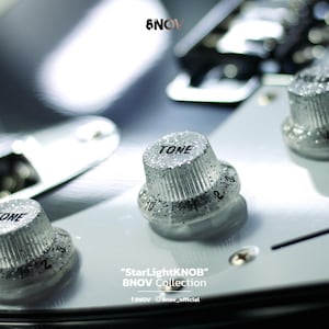 May include: Silver glitter guitar control knobs labelled TONE on a white pickguard. The knobs feature vertical ridges and black numerical markings. The text 8NOV, StarLightKNOB, 8NOV Collection, and social media handles are visible on the image.