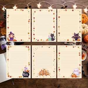 May include: Six sheets of cream-colored stationery with horizontal lines, each featuring a unique border of autumn leaves and Halloween-themed illustrations including a witch, a black cat with a cauldron, a bat, a ghost, and pumpkins.