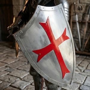 May include: A silver-colored shield with a prominent red cross design. The shield is edged with rivets and appears to be made of metal. The shield is held by a person wearing armor, suggesting a medieval or historical theme.
