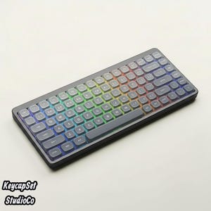 May include: A compact mechanical keyboard featuring dark gray, translucent keycaps with white lettering. The keyboard has a black frame and displays a vibrant, multi-colored RGB backlight that illuminates the spaces between the individual keys.