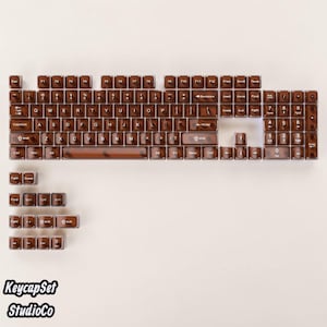 May include: A full set of translucent brown mechanical keyboard keycaps featuring white QWERTY layout lettering. The collection includes standard alphanumeric keys, function keys, a numeric keypad, and various modifier keys with standard symbols.