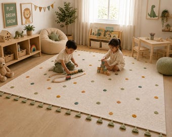 May include: A large, rectangular, off-white area rug featuring a repeating pattern of small, raised, circular tufts in muted shades of sage green and mustard yellow, finished with a row of sage green tassels along the bottom edge.