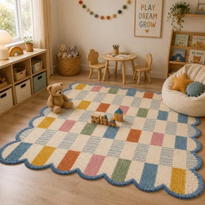 May include: A rectangular area rug with a scalloped blue border, featuring a grid pattern of cream-colored squares alternating with textured rectangular blocks in shades of yellow, orange, pink, green, and blue, laid out on a wooden floor.