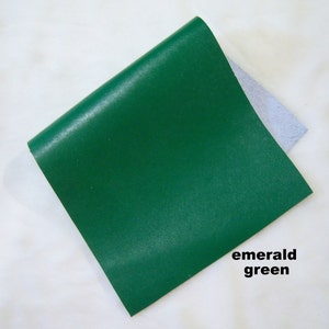May include: A square piece of emerald green leather. The leather is smooth and has a slight sheen.