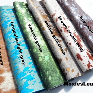 May include: Five different colours of cowhide leather with a white background. The colours are caramel cream, turquoise/light grey, emerald green, antique gold/cream, brown cream pony, and brown/silver. The text "MoxiesLeather" is at the bottom of the image.