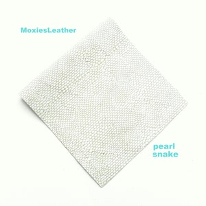 May include: A white leather sheet with a textured snake skin pattern. The text "MoxiesLeather" is in the top left corner and "pearl snake" is in the bottom right corner.