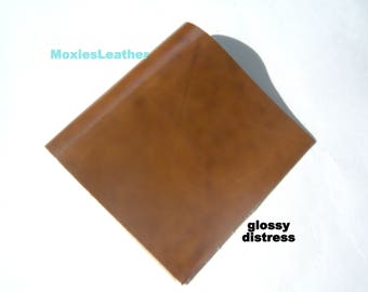 May include: A piece of brown leather with a glossy distressed finish.  The leather is smooth and has a slight sheen.  MoxiesLeather is printed in the top left corner.