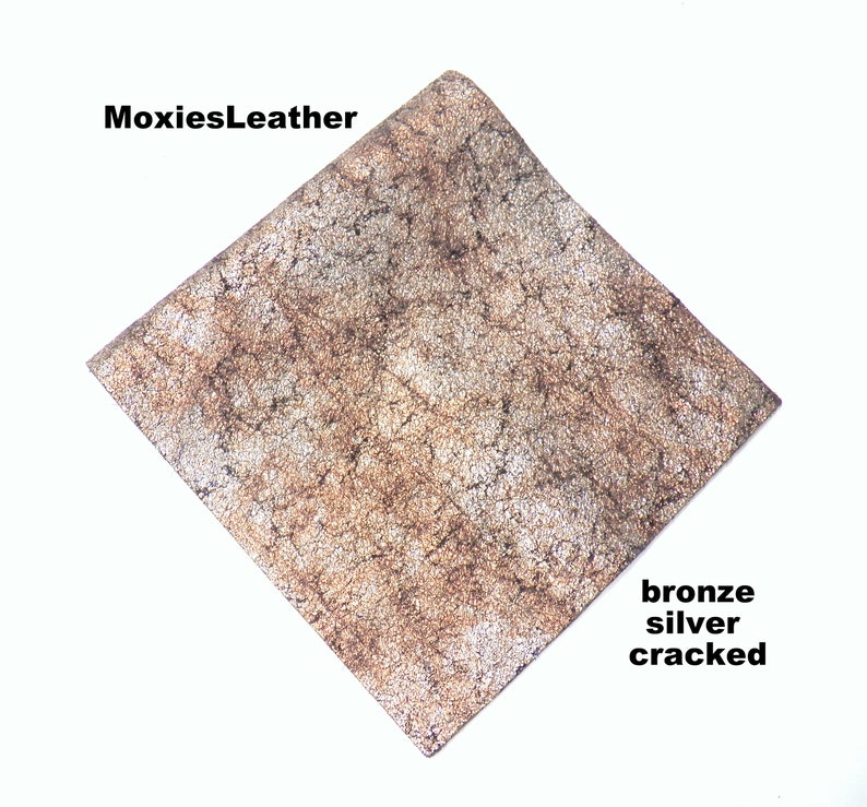 Puede incluir: Primer plano de un trozo de cuero agrietado con un acabado met&aacute;lico bronce y plateado. El cuero tiene un aspecto texturizado y envejecido. MoxiesLeather.