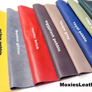 May include: A selection of leather swatches in various colours and textures, including black pebble, ochre pebble, denim glitter, rustic brick, eggplant pebble, taupe grey, royal pebble, sage pebble, and teal pebble. The swatches are displayed in a row, with the text "MoxiesLeather" visible at the bottom of the image.