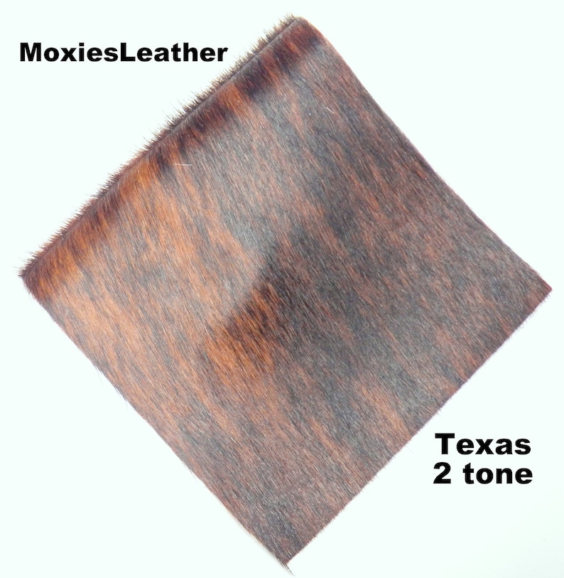 May include: A close-up of a piece of brown and black cowhide leather with a short, soft nap. The leather has a two-tone pattern and is labeled "Texas 2 tone".