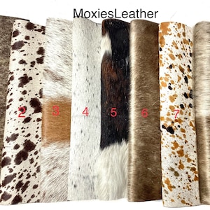 May include: Eight different cowhide rugs in various colours and patterns. The rugs are all approximately the same size and are arranged in a row. The rugs are numbered 1 through 8.