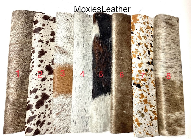 May include: Eight different cowhide rugs in various colors and patterns. The rugs are all approximately the same size and are arranged in a row. The rugs are numbered 1 through 8.