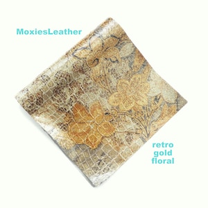 May include: A square piece of gold faux leather with a retro floral pattern. The leather has a textured, cracked surface.