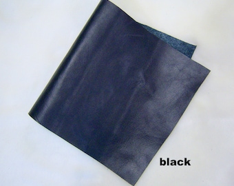 May include: A piece of dark blue leather. The leather is smooth and has a slight sheen. The leather is folded in half and the word "black" is written below it.