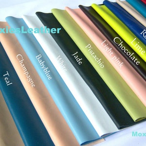 May include: A selection of leather swatches in various colours, including black, tan, teal, champagne, baby blue, white, jade, pistachio, light pink, chocolate, lime, royal blue, cream, turquoise, and red. The swatches are arranged in a row, with the darkest colours on the left and the lightest colours on the right. The text "MoxiesLeather" appears twice in the image.