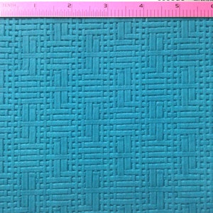 Puede incluir: Primer plano de una tela azul turquesa texturizada con un patrón tejido. La tela se mide con una regla rosa.