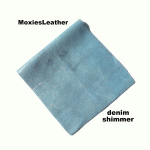 May include: A light blue leather fabric with a denim shimmer finish. The fabric is textured and has a subtle sparkle.