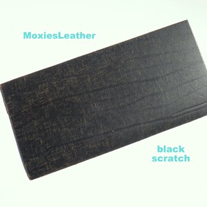 Puede incluir: Una muestra de cuero negro con un patrón texturizado sutil y un pequeño rasguño.