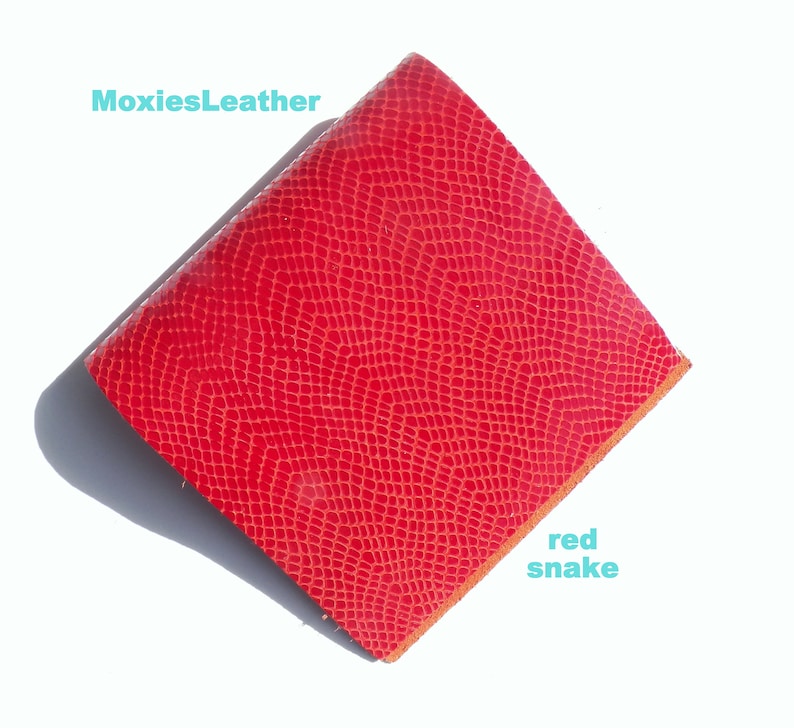 May include: Red snake embossed leather, a textured material with a red colour. MoxiesLeather.