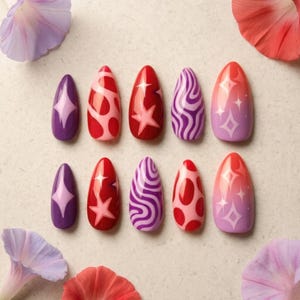May include: A set of ten almond-shaped press-on nails featuring various designs including purple with light purple stars, red with pink abstract shapes, red with pink stars, purple and pink swirls, and a pink to purple gradient with white stars.