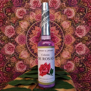 Może przedstawiać: Fioletowa szklana butelka "Colonia DE ROSAS" firmy Murray & Lanman, ze srebrną nakrętką i etykietą z ilustracją czerwonej róży. Butelka zawiera 221 ml płynu, na tle kwiatowym.