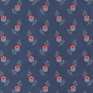 May include: A navy blue fabric with a repeating pattern of red and white shield-like shapes, each topped with three red stars. The shields are interspersed with sprigs of gray leaves, creating a patriotic and decorative design.