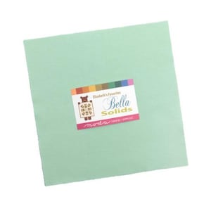 May include: A square of solid light green fabric with a label that reads "Elizabeth's Favorites Bella Solids" in white script. The label has a colorful stripe across the top and a bear graphic. The fabric is likely for quilting or sewing projects.