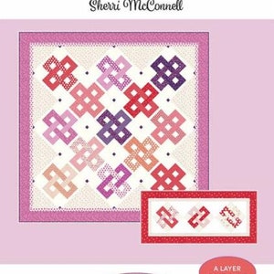 May include: A quilting pattern design by Sherri McConnell, featuring a quilt with interlocking geometric shapes in shades of red, pink, and purple. The design includes the text "Daydream" and "A Layer Cake Quilt".